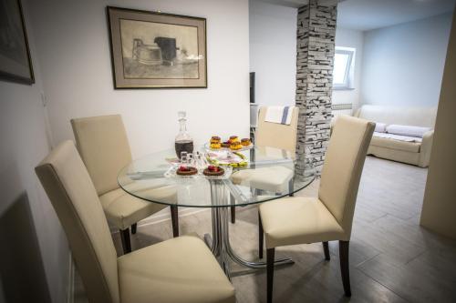 a dining room with a glass table and chairs at Apartman Magnolia in Ivanić-Grad