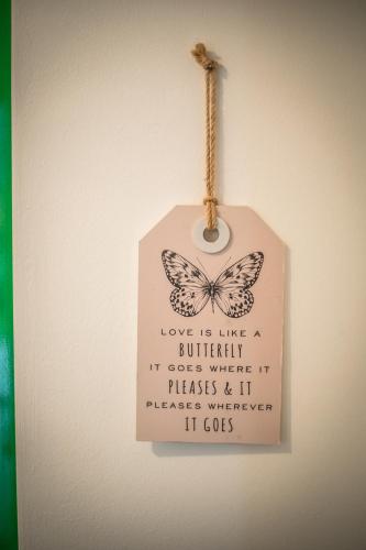 a sign with a butterfly on it hanging on a wall at Apartman Magnolia in Ivanić-Grad