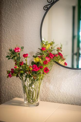 a vase of flowers on a table in front of a mirror at Apartman Magnolia in Ivanić-Grad