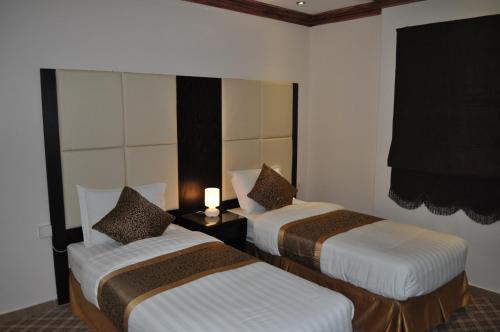 a hotel room with two beds and a candle on a table at Nafa Serviced Apartments نافا للشقق المخدومة الدمام in Dammam