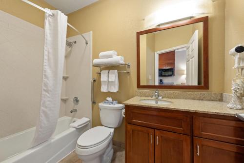 a bathroom with a toilet and a sink and a mirror at Extended Stay America Suites - Houston - IAH Airport in Houston