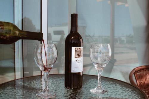 a bottle of wine and two wine glasses on a table at Quintas Marlet en la ruta del vino in Ensenada