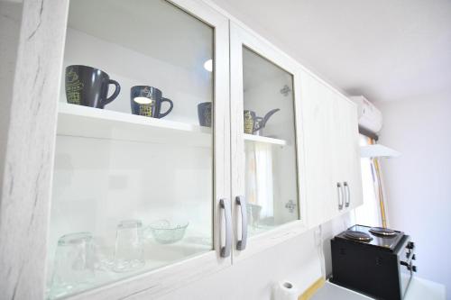 a kitchen cabinet with glass doors and a sink at Vulsa Apartmani in Kladovo