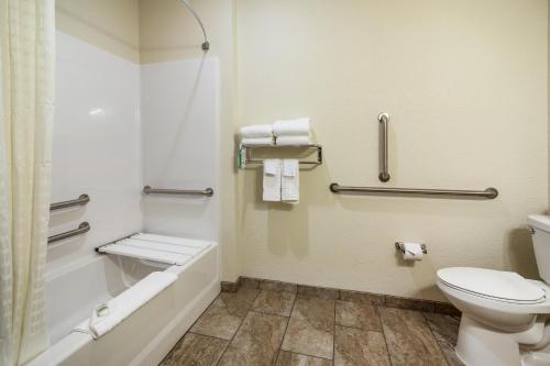 a bathroom with a toilet and a bath tub at Cobblestone Hotel & Suites - Victor in Victor