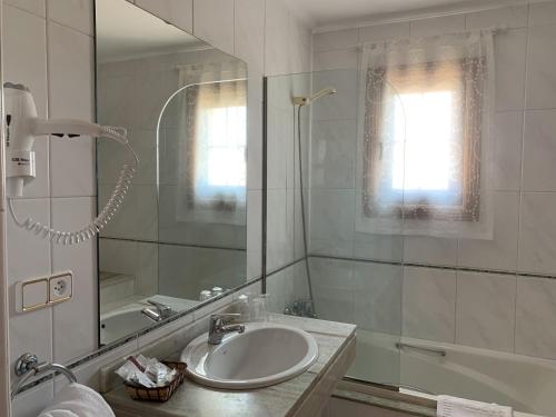 een badkamer met een wastafel, een douche en een spiegel bij Nueva Colina in Tomiño