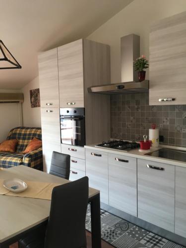a kitchen with white cabinets and a table with chairs at Case Vacanza Sa Mitza in Villamassargia