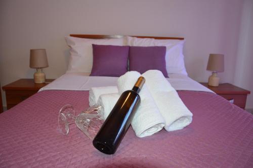 uma cama roxa com toalhas e uma garrafa em Casa al mare Anastasia em Kallikrateia