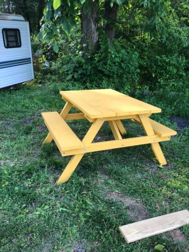 a picnic table with a bench in the grass at Chateau Tina in the Catskill Mountains in East Durham