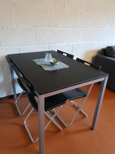 un tavolo nero con due sedie e una ciotola di cibo sopra di Bø Leiligheter a Bø
