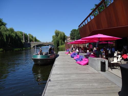 a boat parked next to a dock with people sitting on pink chairs at Roer, huisje aan de Maas in Maren-Kessel