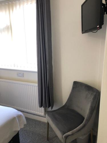 1 dormitorio con silla y TV en la pared en The Bell Hotel, en Newtown