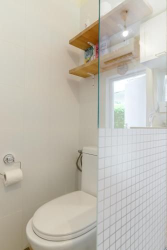 a white bathroom with a toilet and a window at Charming Boutique Studio - TLv Center in Tel Aviv