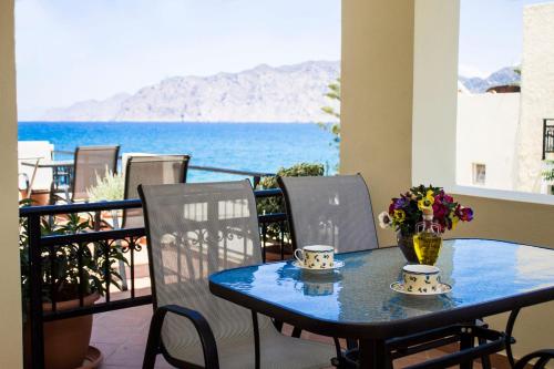 a table with two cups and flowers on a balcony at Sun & Sea in Mochlos