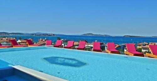 a swimming pool with chairs and the ocean in the background at Ferush Boutique Hotel in Urla