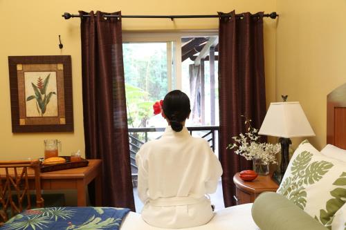 a woman sitting on a bed looking out of a window at Hawaiian Sanctuary Eco Retreat Center in Pahoa