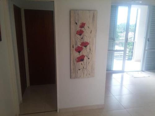 a painting of red flowers on a white wall at JUANA II in Villa Elisa