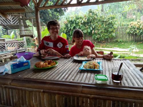 a man and a woman sitting at a table with a baby at De Salak Homestay in Bogor