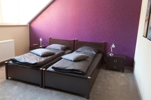 two beds in a room with a purple wall at Apartmany Becherplatz in Karlovy Vary