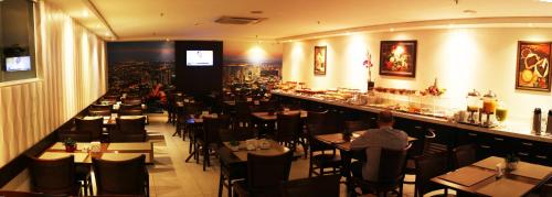 a restaurant with tables and chairs and a bar at Hotel D'Luca in Cuiabá
