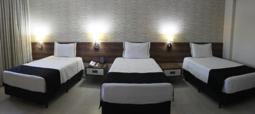 a hotel room with two beds and two lamps at Hotel D'Luca in Cuiabá