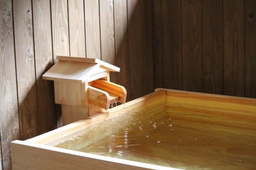 a bath tub filled with water next to a wooden wall at Bosenkan in Gero