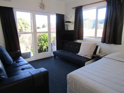 Habitación de hotel con cama, sofá y ventanas en Beachside Sunnyvale Motel en Picton