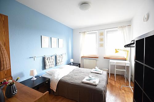 a blue bedroom with a bed and a desk at Mhost Bronowice in Kraków
