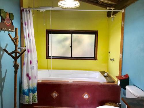 a bath tub in a yellow bathroom with a window at Pousada Recanto da Siriema in Monte Alegre do Sul