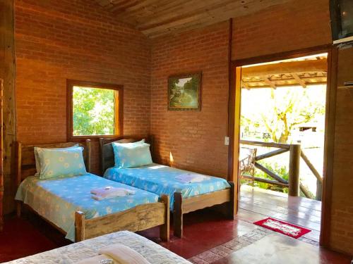 a bedroom with two beds and a door to a porch at Pousada Recanto da Siriema in Monte Alegre do Sul