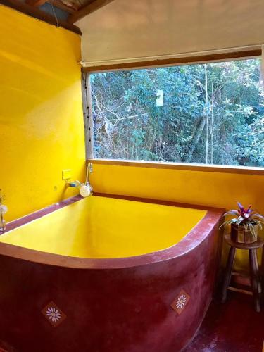 a bath tub in a room with a window at Pousada Recanto da Siriema in Monte Alegre do Sul