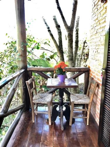 a table with two chairs and a vase of flowers on a porch at Pousada Recanto da Siriema in Monte Alegre do Sul