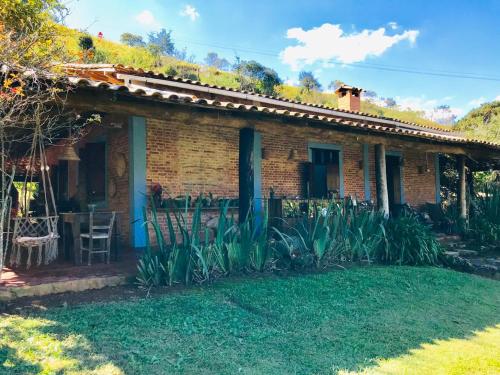 a brick house with a garden in front of it at Pousada Recanto da Siriema in Monte Alegre do Sul