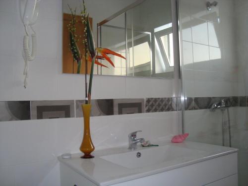 un vase jaune assis sur un lavabo dans la salle de bains dans l'établissement Vila Algarvia Boutique & Suites, à Albufeira