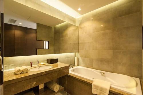 a bathroom with a sink and a bath tub at Green Park Hotel Tianjin in Binhai