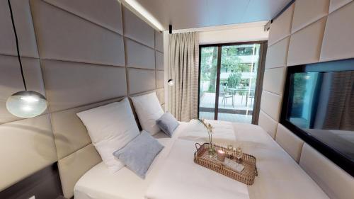 White Pearl Apartment 0.10 في تيميندورفير ستراند: غرفة نوم بسرير ابيض مع تلفزيون