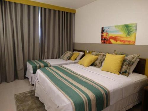 duas camas num quarto de hotel com almofadas amarelas em Apartamento em Resort de Olimpia em Olímpia