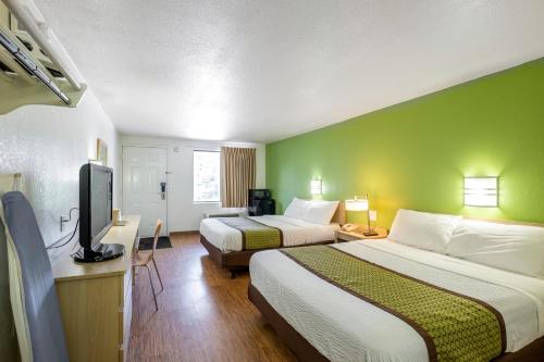 a hotel room with two beds and a flat screen tv at American Inn in Carlisle