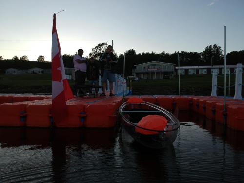 a group of people standing on a dock with a boat at Trailsman Lodge in Baddeck