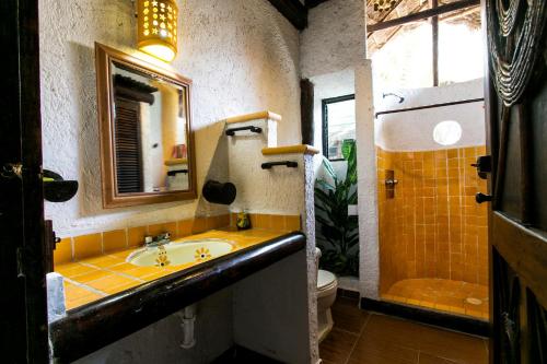 a bathroom with a sink and a toilet and a mirror at Chillaxing Beach Front House in Tulum