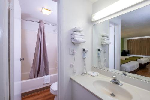 Baño blanco con lavabo y espejo en American Inn, en Carlisle