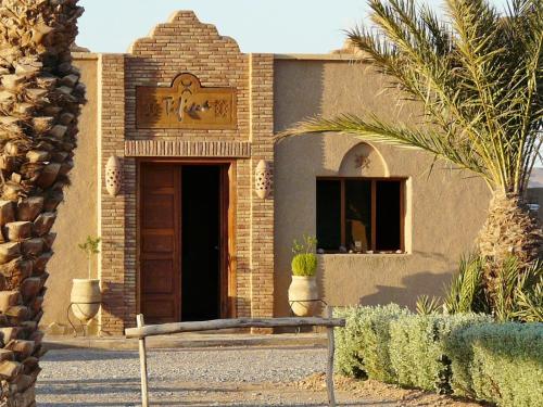 a brick building with a door and a bench in front at Tifina Caravanserail d'Arfoud in Erfoud