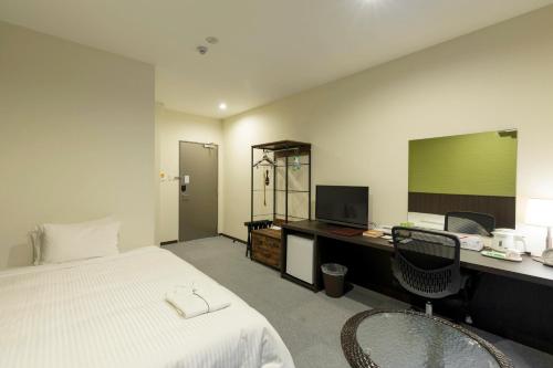 a bedroom with a bed and a desk with a computer at Crown Hotel Okinawa Annex in Okinawa City