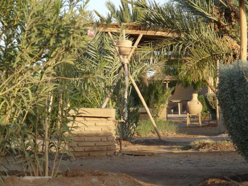 a garden with a street light and palm trees at Tifina Caravanserail d'Arfoud in Erfoud