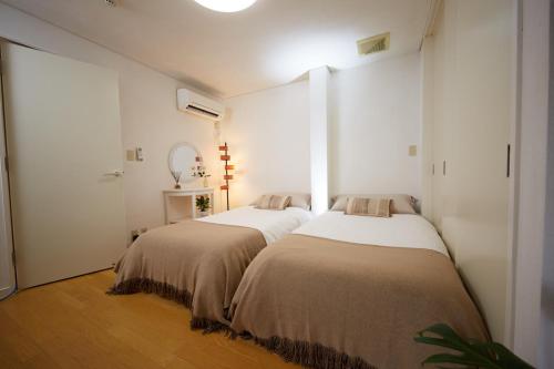 two beds in a room with white walls and wood floors at SHINJUKU 5-ROOM Family house in Tokyo