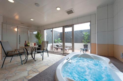 a bath tub in a room with a table and chairs at ホテル マイン 岐阜 in Ginan