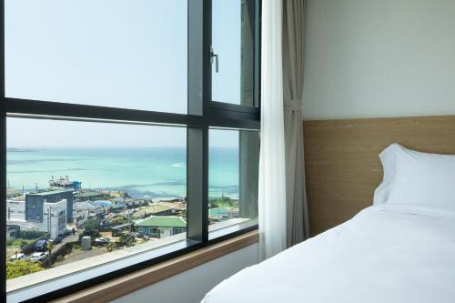 a bedroom with a window with a view of the ocean at Lemain Hotel in Jeju