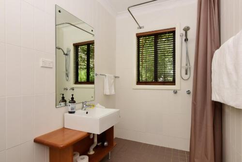 ein weißes Badezimmer mit einem Waschbecken und einem Spiegel in der Unterkunft Cloudsong Chalet 1 Close to the village centre in Kangaroo Valley