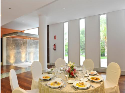 a dining room with a table and white chairs at Hotel Salobreña Suites in Salobreña