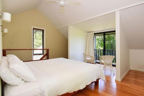 1 dormitorio con 1 cama grande y balcón en Cloudsong Chalet 3 Close to the village centre en Kangaroo Valley