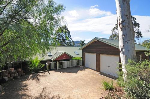 a house with a garage and a tree at Bonnie Doon Family friendly home in Kangaroo Valley